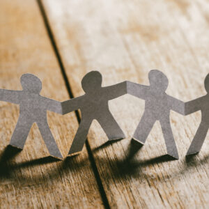 Paper People Holding Hands on a Wooden Table